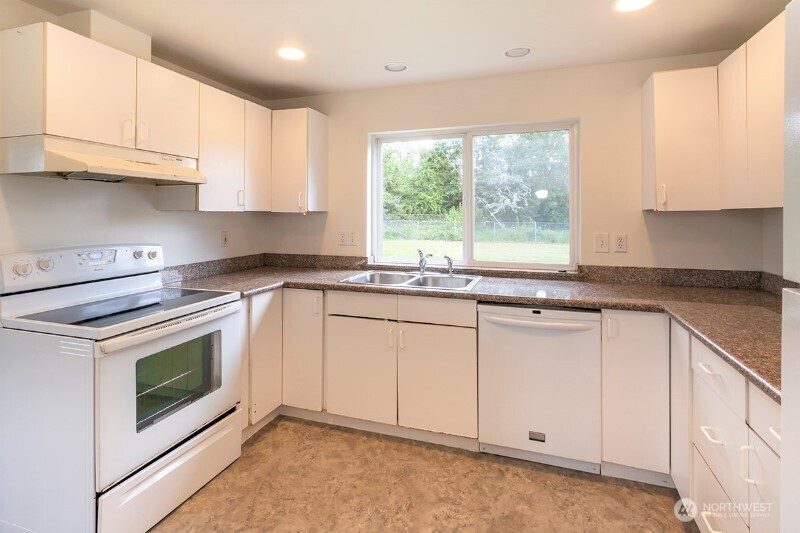 551 South Sullivan Street Seattle, WA 98108 - Photo 12 of 24 a kitchen with granite countertop white cabinets white appliances a sink and a window