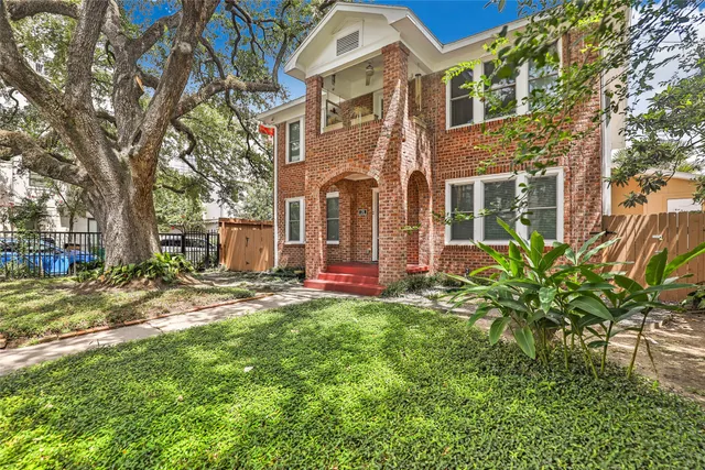 a view of a brick house with a big yard and large trees