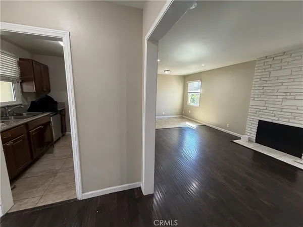 an empty room with wooden floor fireplace and windows