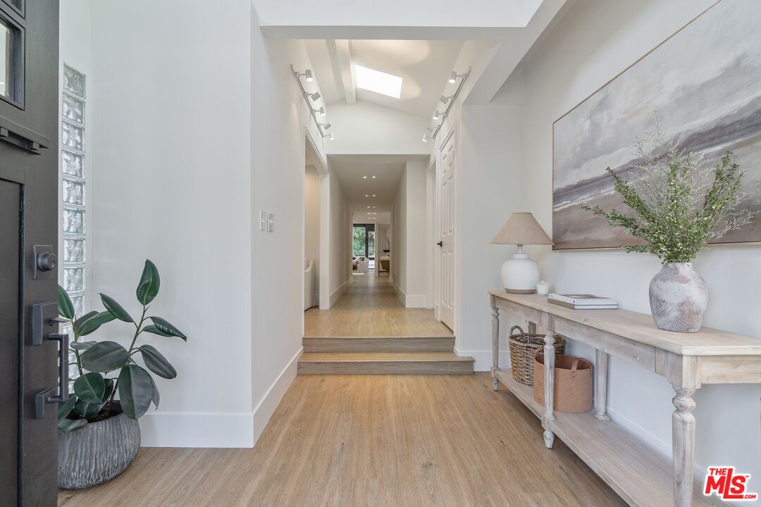 22801 Pera Road Woodland Hills, CA 91364 - Photo 19 of 46 a view of a hallway to a livingroom with wooden floor and a chandelier