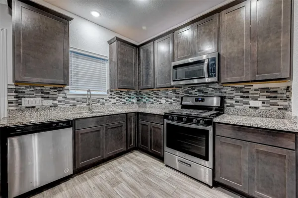a kitchen with stainless steel appliances granite countertop wooden cabinets stove top oven and sink