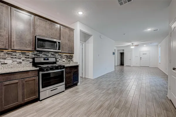 a kitchen with stainless steel appliances kitchen island granite countertop a stove a sink and a microwave