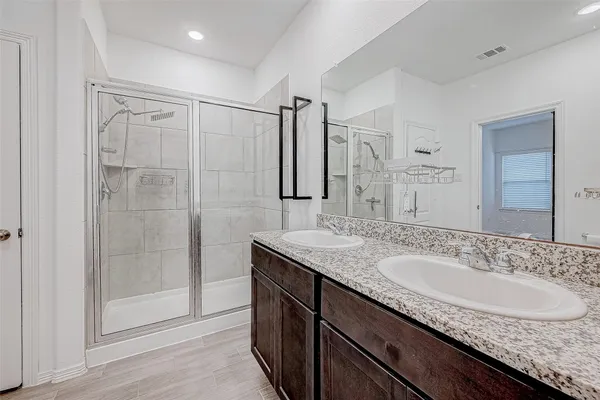 a bathroom with a granite countertop sink a mirror a glass door a shower and vanity