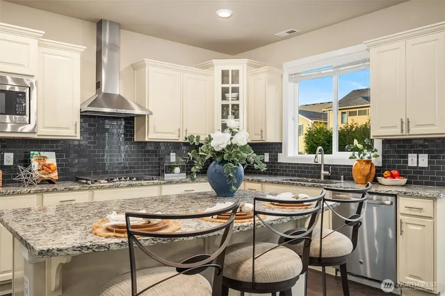 a kitchen with granite countertop a sink chairs and cabinets