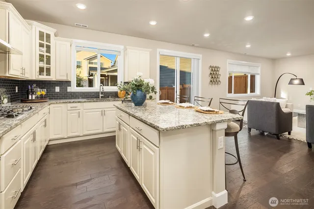a kitchen with granite countertop sink stove and white cabinets with wooden floor