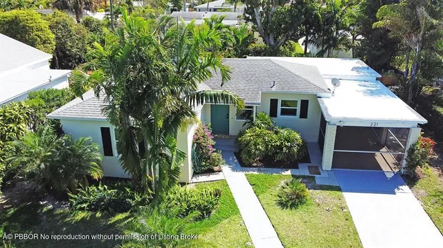 a view of a house with potted plants and a large tree