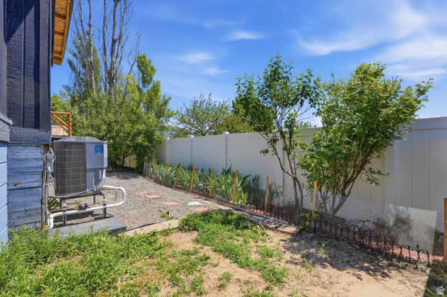 2500 North Fort Lane, Unit 220 Layton, UT 84041 - Photo 23 of 23 Side yard featuring a gravel pathway with stepping stones, mature trees, and a privacy fence