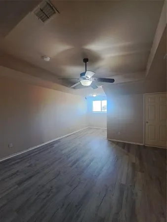 an empty room with wooden floor chandelier fan and windows