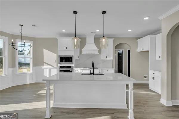 an empty room with wooden floor chandelier fan and windows