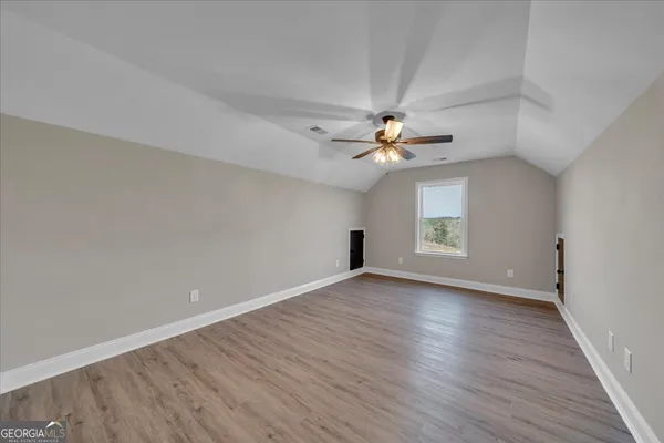 a view of an empty room with cabinet and a ceiling fan