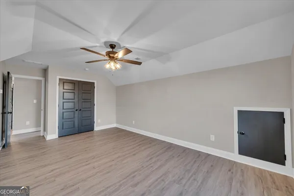 an empty room with wooden floor chandelier fan and windows