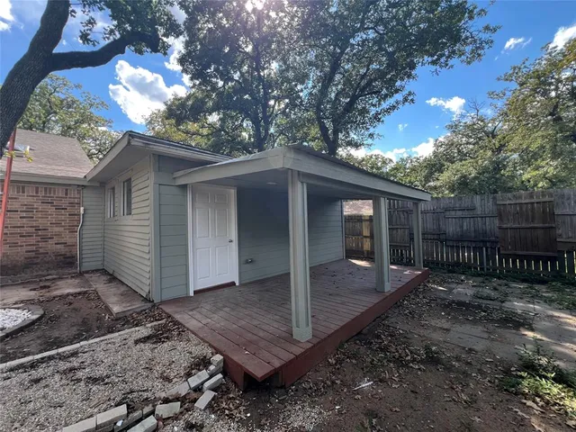 a view of a house with a small yard tree and wooden fence