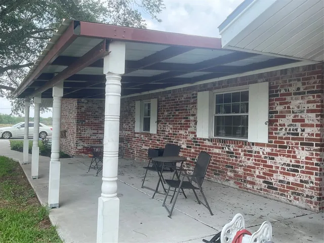 a patio with table and chairs and potted plants