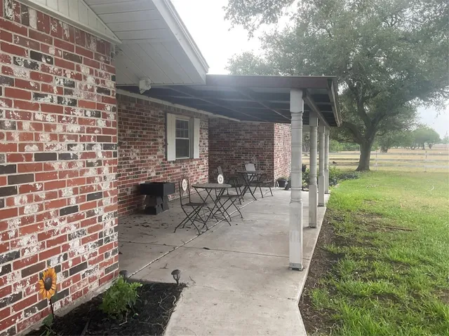 a view of a backyard with table and chairs with plants and wooden fence