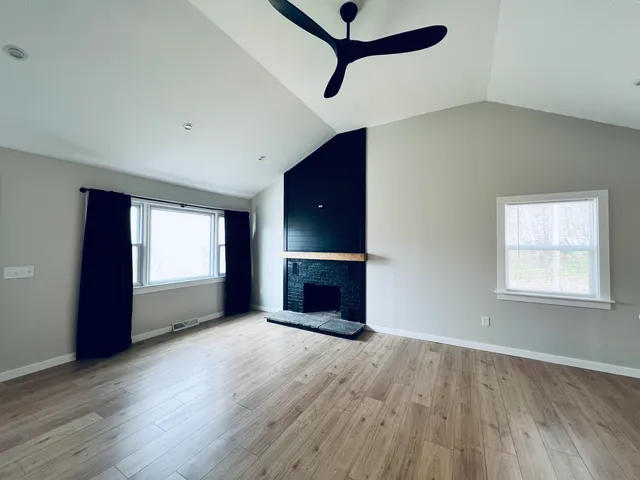 an empty room with windows and fireplace