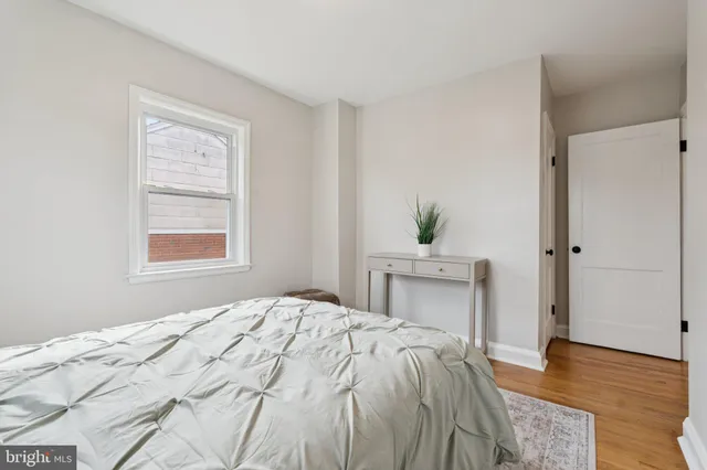 a bedroom with a bed potted plant on dresser and a window