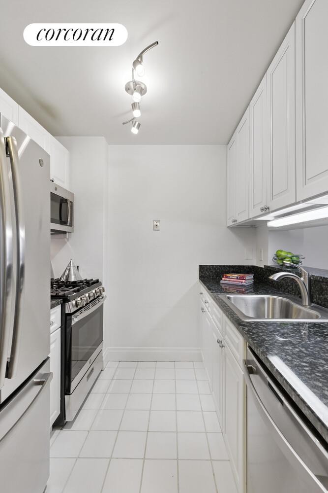 404 East 76th Street, Unit 2J Manhattan, NY 10021 - Photo 3 of 9 a kitchen with granite countertop a sink and stainless steel appliances