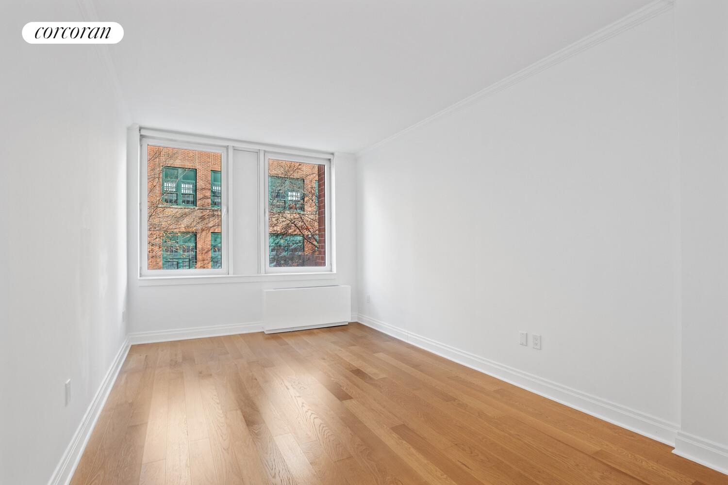 404 East 76th Street, Unit 2J Manhattan, NY 10021 - Photo 4 of 9 an empty room with wooden floor and windows
