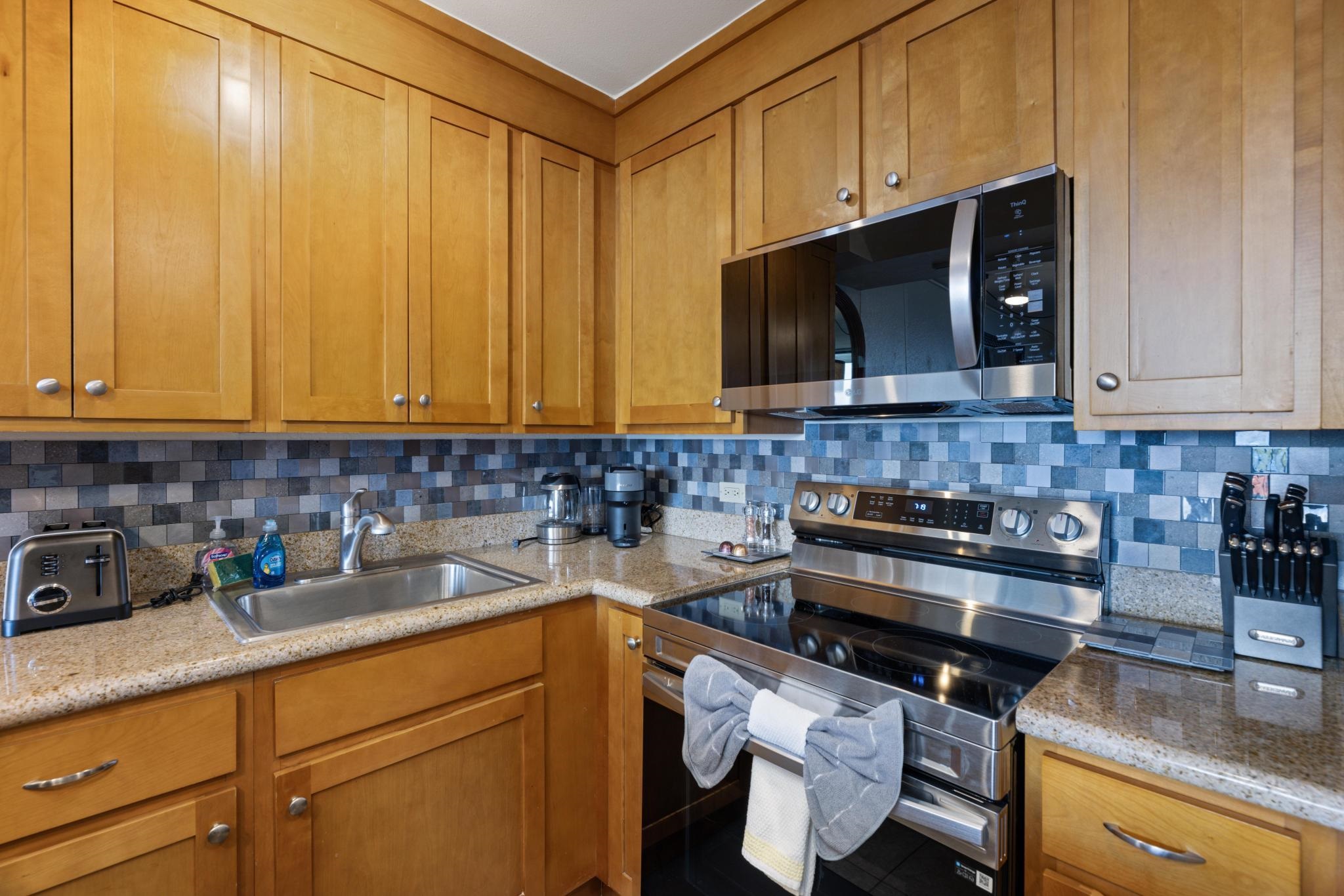 3445 Lower Honoapiilani Road, Unit 826 Lahaina, HI 96761 - Photo 10 of 26 a kitchen with stainless steel appliances granite countertop a stove a microwave and cabinets