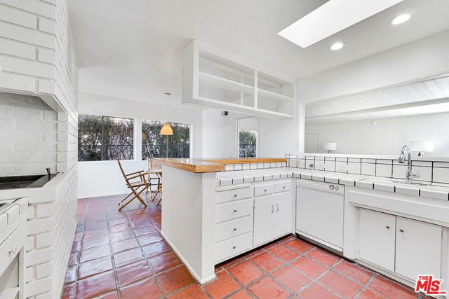 a kitchen with a sink dishwasher a dining table and chairs with wooden floor