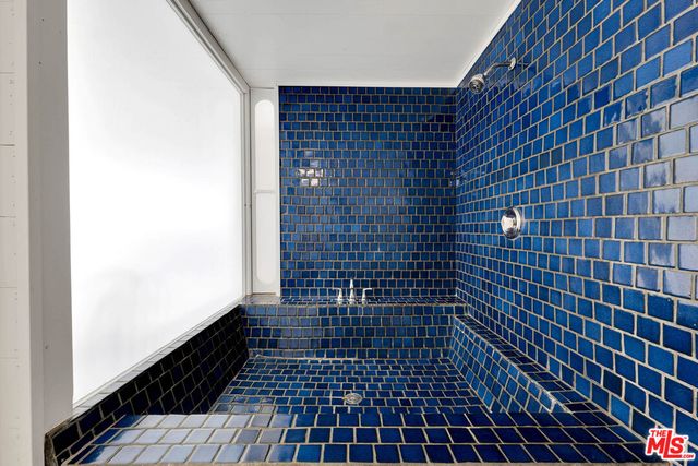 a bedroom with a bed a window and potted plant on table