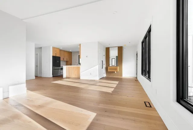 a view of a hallway with wooden floor and a living room