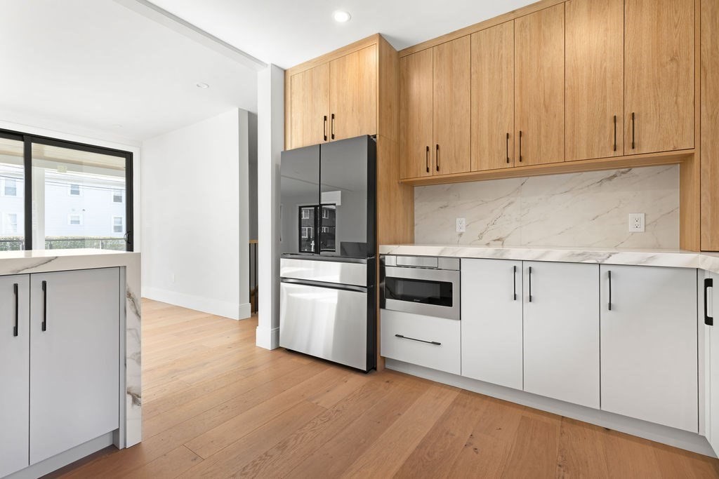 265-267 River Street, Unit 267 Newton, MA 02465 - Photo 8 of 22 a kitchen with granite countertop white cabinets and stainless steel appliances