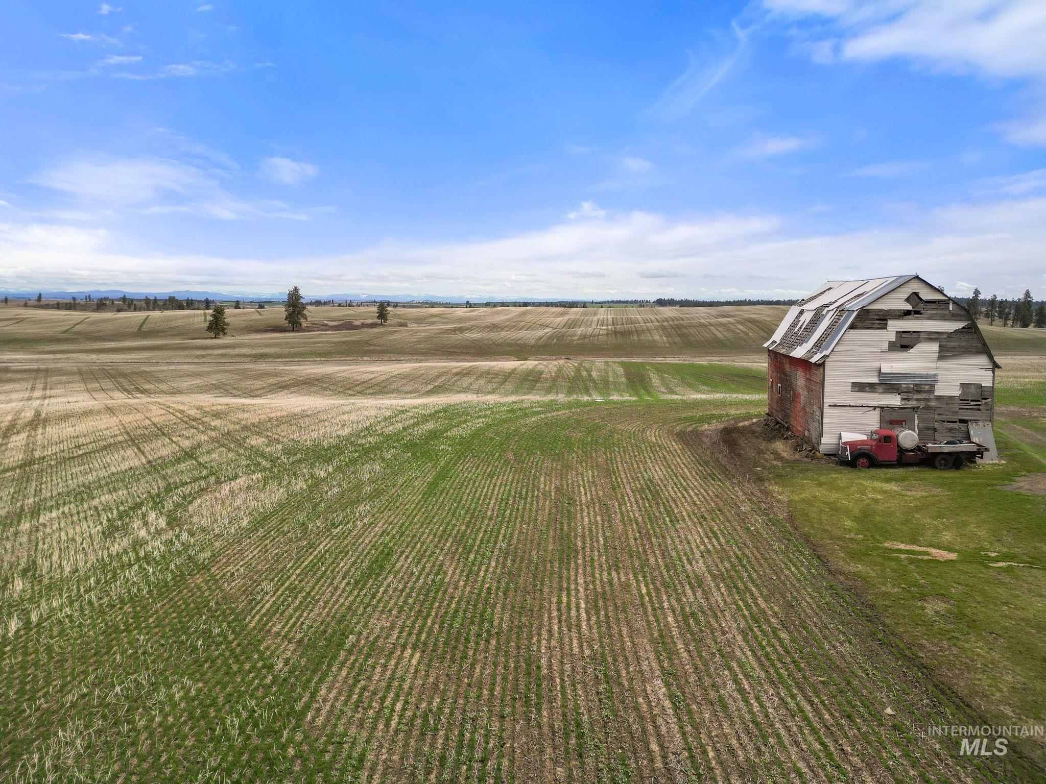 View of green lawn featuring a barn, a view of countryside, an outbuilding, and agricultural area