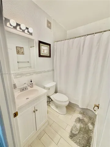 a bathroom with a sink a toilet and shower curtain