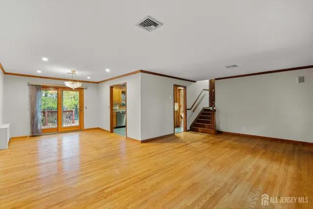 a view of an empty room with wooden floor and stairs