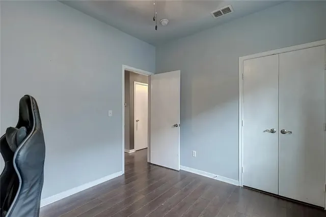 an empty room with wooden floor and a ceiling fan