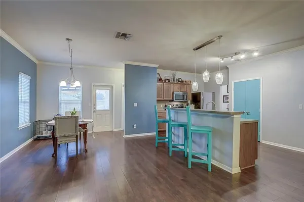 a kitchen with stainless steel appliances kitchen island granite countertop a table chairs refrigerator and sink