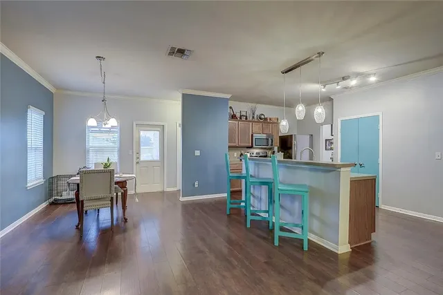 a kitchen with stainless steel appliances kitchen island granite countertop a table chairs refrigerator and sink