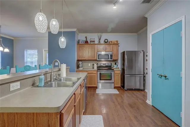 a kitchen with stainless steel appliances granite countertop a refrigerator a sink dishwasher a stove and a dining table with wooden floor