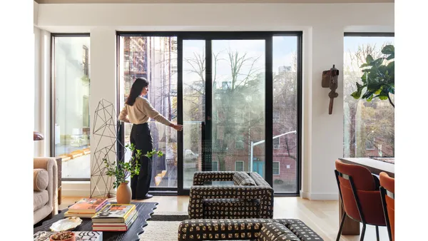 a living room with furniture a potted plant and a large window