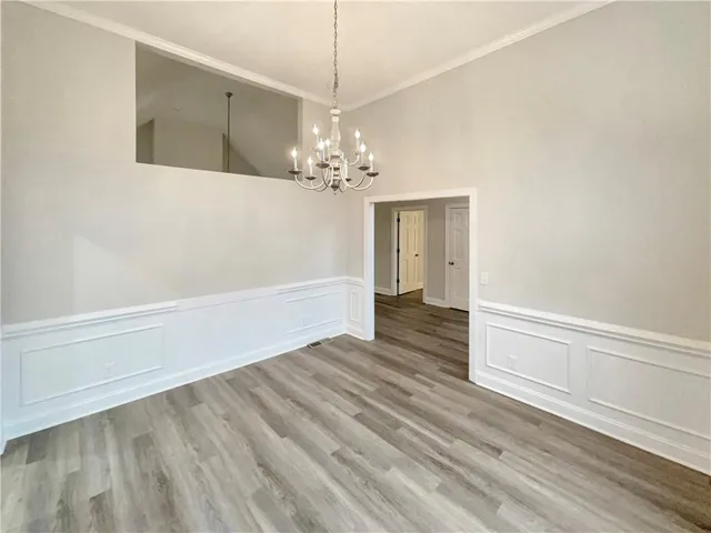 a view of a hallway with wooden floor and chandelier