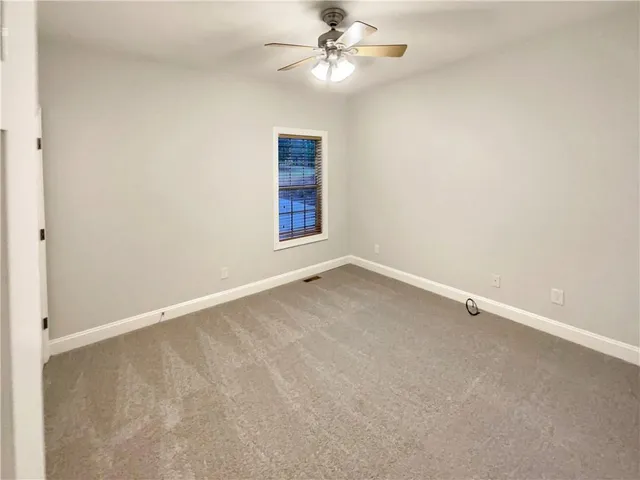 an empty room with a window and ceiling fan