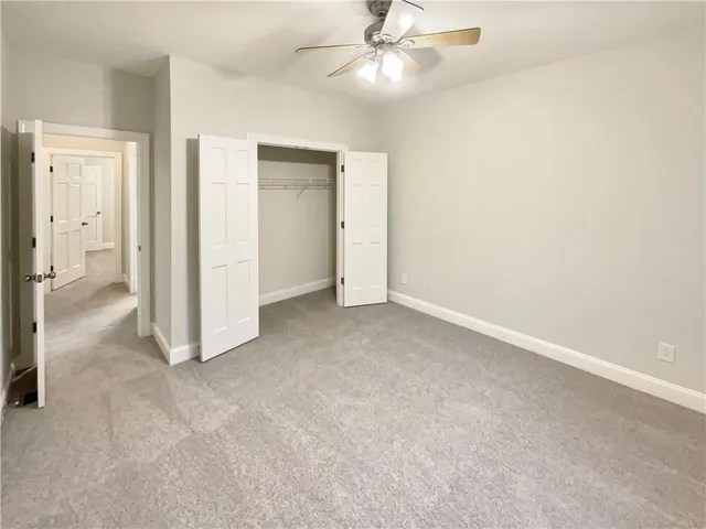 an empty room with closet and a ceiling fan