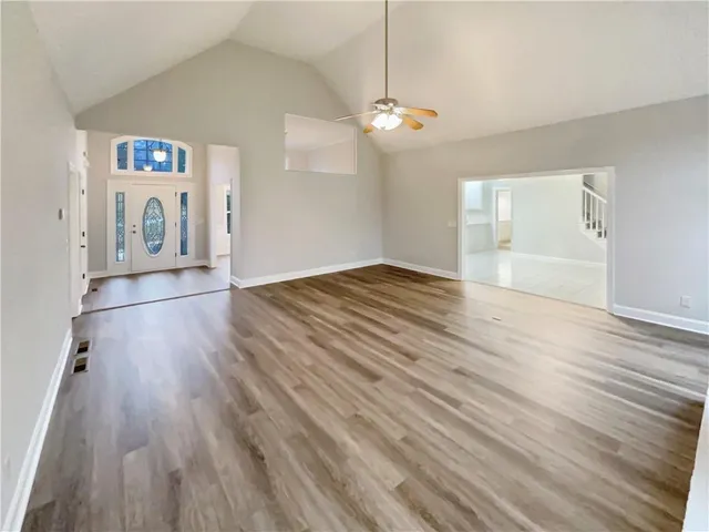 an empty room with wooden floor chandelier and windows
