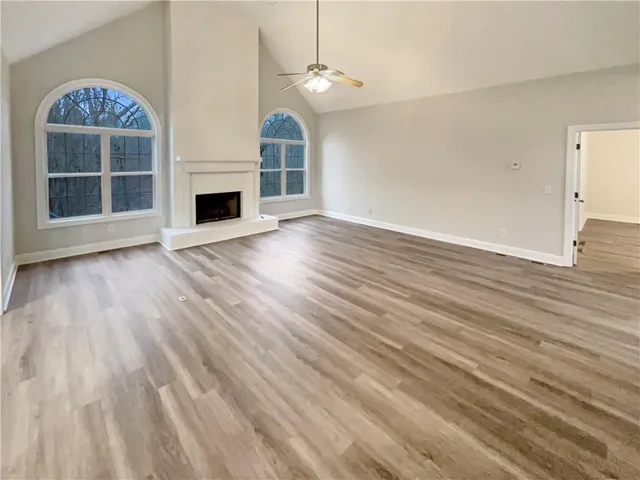 an empty room with wooden floor fireplace and windows