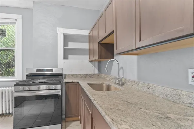 a kitchen with granite countertop a stove sink and cabinets