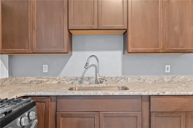 a sink with granite countertop white cabinets and a sink