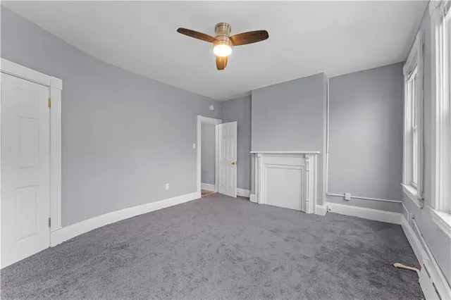 a view of an empty room with a ceiling fan and window