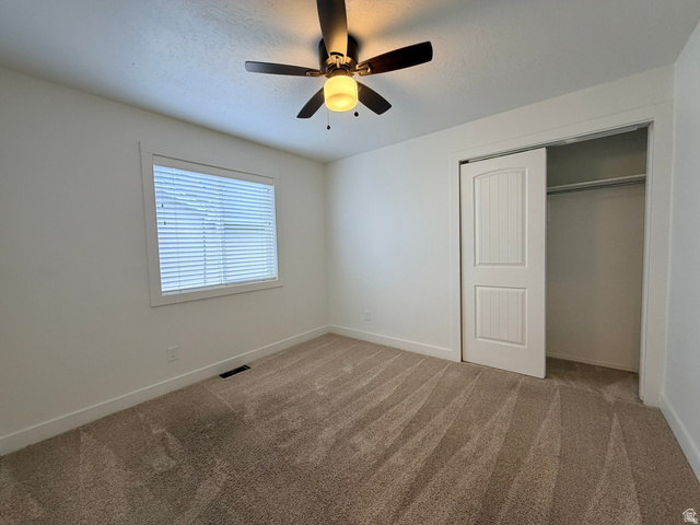 11895 Inauguration Road Draper, UT 84020 - Photo 6 of 10 Bright secondary bedroom featuring neutral carpeting, a ceiling fan with integrated lighting, and a spacious walk-in closet with bifold doors and shelving