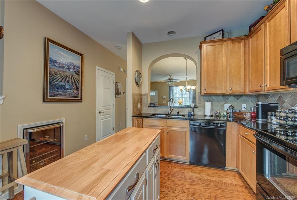 220 Falling Ridge, Unit 149 Mount Holly, NC 28012 - Photo 9 of 19 a kitchen with kitchen island granite countertop a stove top oven a sink a dining table and chairs with wooden floor