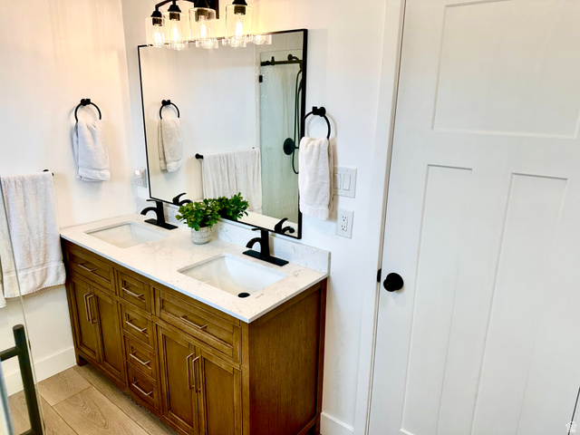 7818 North Windhover Road Eagle Mountain, UT 84005 - Photo 14 of 32 Double vanity with a light wood-finish cabinet and white countertop, featuring dual sinks and matte black fixtures