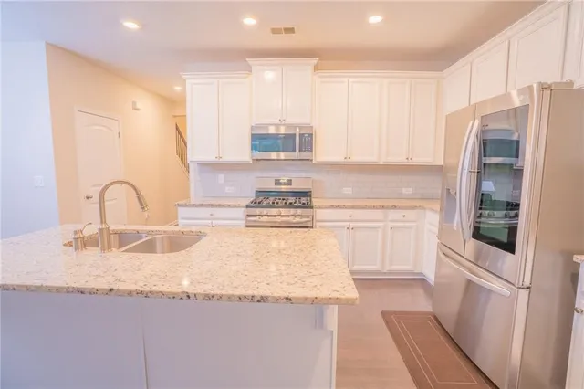 a kitchen with granite countertop a refrigerator stove top oven and sink