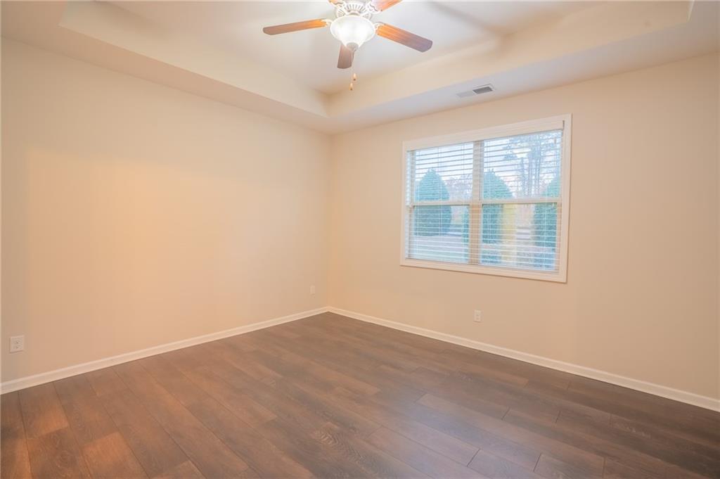 2420 Boxwalking Court Cumming, GA 30040 - Photo 19 of 42 an empty room with wooden floor chandelier fan and windows
