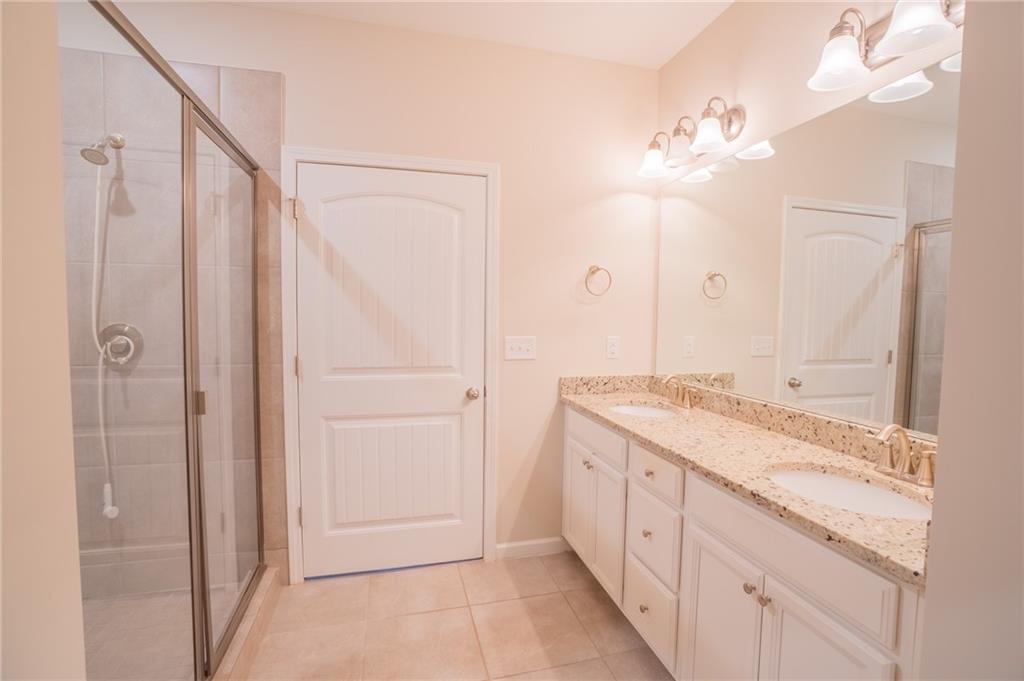 2420 Boxwalking Court Cumming, GA 30040 - Photo 25 of 42 a spacious bathroom with a granite countertop sink a mirror and shower