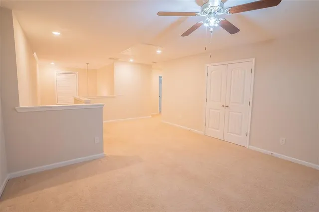 an empty room with chandelier fan and windows
